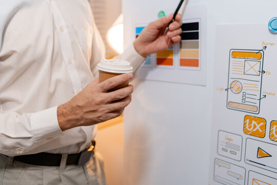 Close-up of a UX designer reviewing wireframes, interface layouts, and visual design elements on a planning board for user interface development, usability testing, and digital product design.