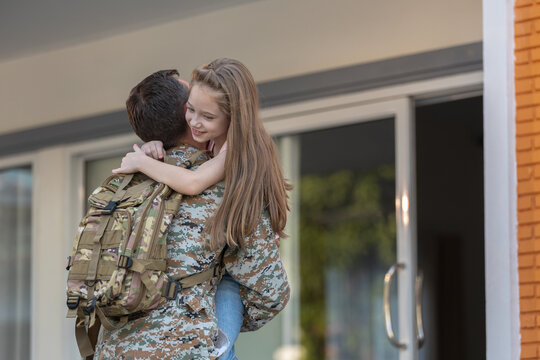 Happy military soldier father return home for family reunion, holding his young daughter in loving hug. Emotional moment of serviceman coming back from deployment