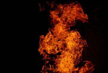 Fototapeta premium Bright orange flames rising against a dark background, illustrating fire, heat, combustion, energy, danger, and abstract fire textures with copy space.