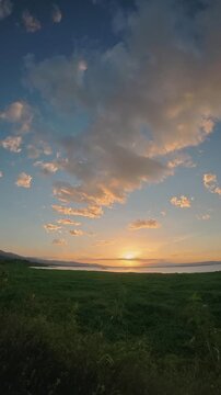 Timelapse of Sunset Over Calm Water and Grassy Field