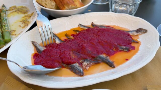 Spanish Tapas Anchovies with Red Pepper Sauce Served on White Plate