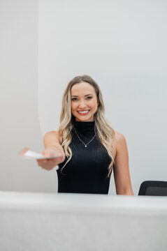 Receptionist standing behind front desk handing out a card brochure
