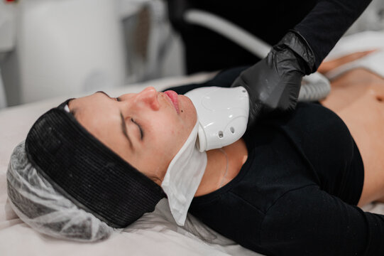Aesthetic practitioner performing laser therapy on clients neck and jawline