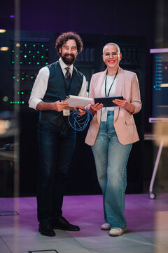 It professionals smiling, collaborating in data center, discussing network technology and cloud computing solutions