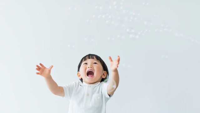 シャボン玉で遊ぶ笑顔の3歳の男の子