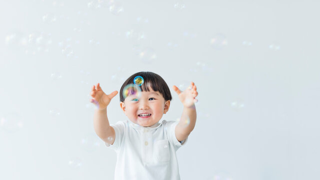 シャボン玉で遊ぶ笑顔の3歳の男の子