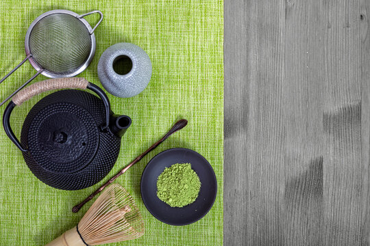 Matcha tea ceremony set with iron teapot, bamboo whisk, scoop and green powder in bowl. Traditional Japanese wellness drink preparation. Zen lifestyle, healthy detox, organic concept