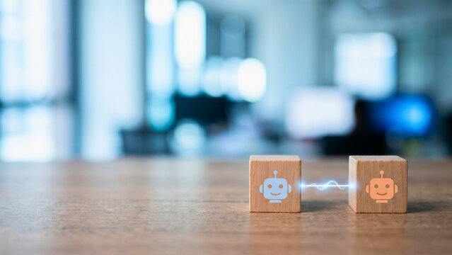 Two wooden cube blocks with differently colored robot icons facing each other with thin glowing line between them, AI agent negotiation concept, multi-agent interaction, automated dialogue