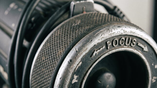 Close up of a dusty textured metal focus knob with engraved arrows on a vintage theatre spotlight