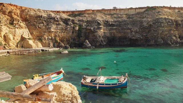 Traditional luzzu boats floating on turquoise water in Anchor Bay Malta