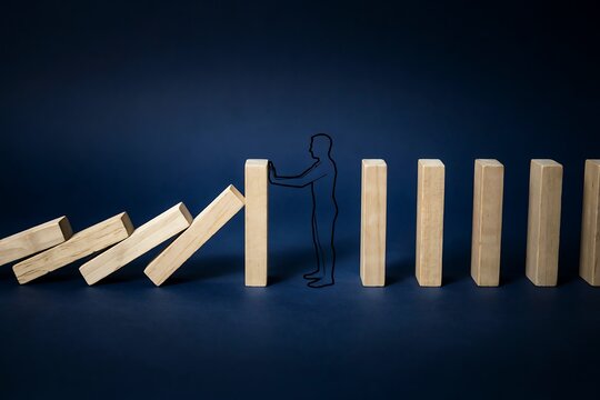 Human silhouette stopping a domino effect, illustrating crisis management, problem solving, and prevention of chain reactions