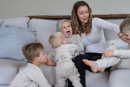 Young boys surrounding mum on the couch having fun