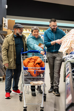 Three generations of family members choosing clothes while shopping in a supermarket