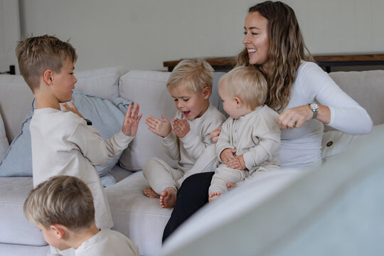 Young boys snuggling with mum on the couch interacting with older brother