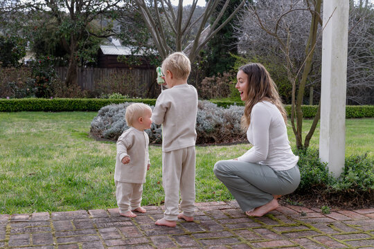 Mum with two young boys outside with a bubble stick