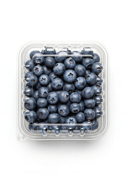 A top-down view of fresh, ripe blueberries packed neatly inside a clear plastic clamshell container, resting against a clean white background