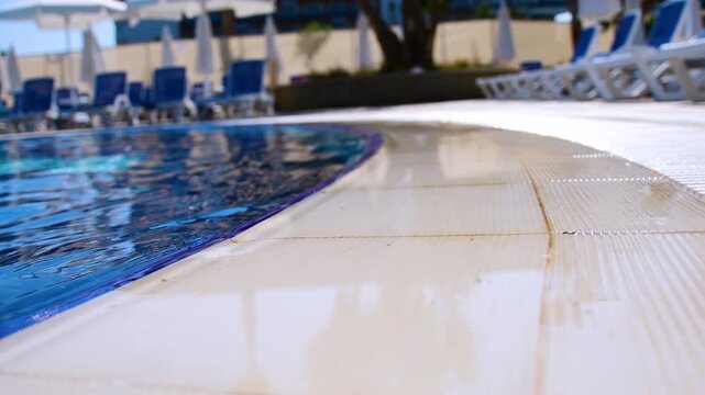 Sunlit hotel pool deck with empty loungers and umbrellas in soft focus. Calm resort scene evoking relaxation and summer escape