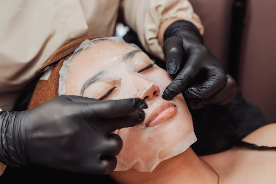 Applying soothing sheet mask after hydradermabrasion facial on Southeast Asian woman to calm skin, restore hydration and enhance post treatment recovery