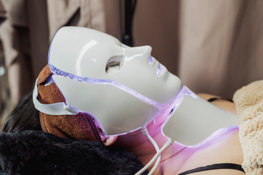 Purple LED light therapy mask on Southeast Asian woman to support skin healing, improve cell renewal and enhance post treatment rejuvenation