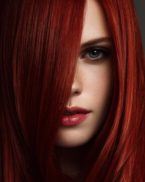 Redhead woman with hair covering face on gray background