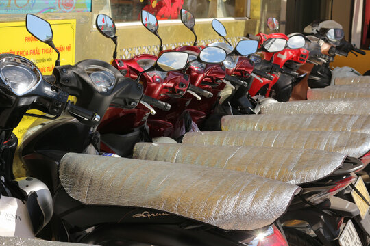 NHA TRANG, VIETNAM - JANUARY 26, 2026: Row of parked scooters covered with sun protection mats to prevent overheating during extreme hot weather.