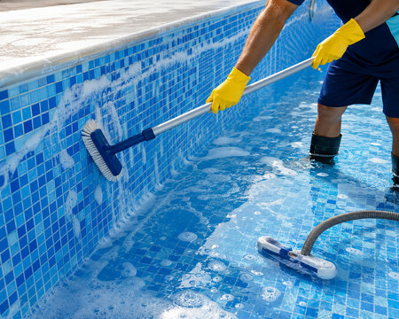 Pool maintenance worker cleaning swimming pool with brush