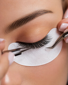 Beautician applying eyelash extensions to closed eye