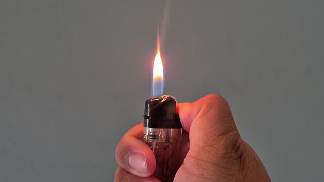 Person sparking a cigarette lighter creating a bright orange flame