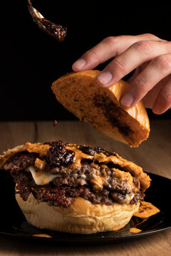 Triple Smash Burger with two sauces and cheese, topped with a teaspoon of sauce.