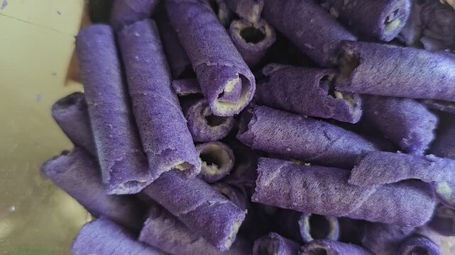 Detailed macro view of delicious ube flavored rolled wafer biscuits stacked together displaying a crispy exterior and sweet cream center