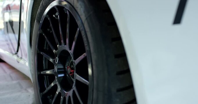 Close-up side view of a black multi-spoke alloy wheel with a low-profile tire on a white sports car