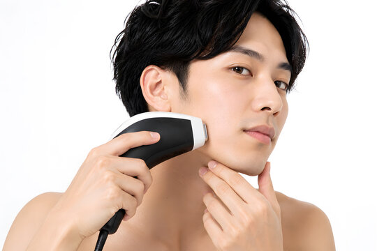 Young man shaving his beard with an electric trimmer
