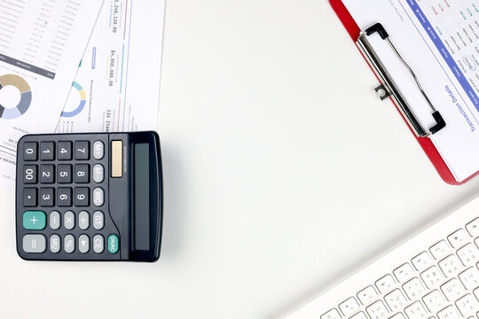 Top view of office desk with calculator, keyboard, and financial reports around copy space. Concept of accounting workspace, budget planning, data analysis, and business background.