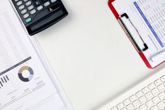 Top view of office desk with calculator, keyboard, and financial reports around copy space. Concept of accounting workspace, budget planning, data analysis, and business background.