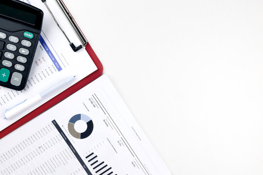 Top view of financial report documents with a calculator and pen near copy space on white background. Concept of business data analysis, budget planning, and accounting workspace.