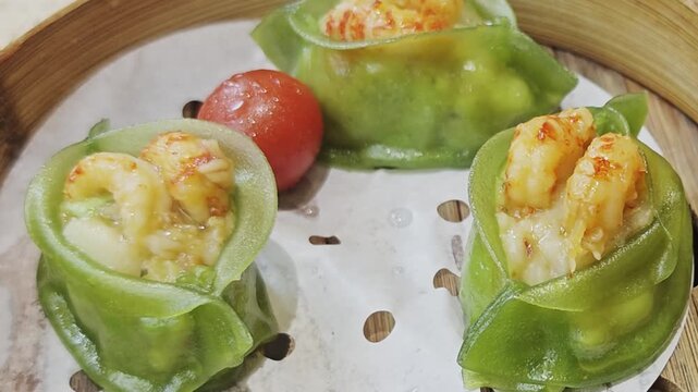A bamboo steamer filled with beautifully crafted green-dipped shrimp-filled dimsums arranged in a circular pattern