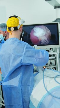 Medical specialist performs minimally invasive surgery with endoscopic camera guide. Surgeons watch nasal endoscopy procedure on screen vertical shot