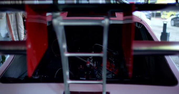 High angle view through the large rear spoiler wing looking into the engine bay of a racing car