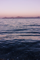 Obraz premium Calm sea in northern Mallorca at sunset with a lone person paddleboarding 
