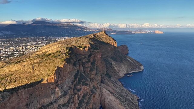 Sunlit coastal headland with ocean, marine geologist surveying rugged rock faces from drone, steep cliffs