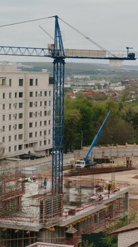 Industrial timelapse of a construction site featuring a tower crane rotating and workers building the foundation and structure of a new modern building in an urban environment during the day