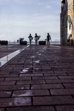 Surfers leaving wet footprints on the promenade in Gran Canaria, Spain