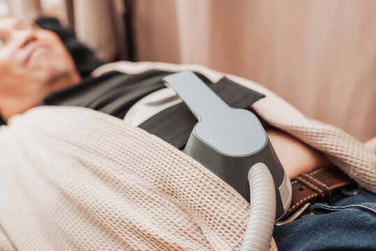 Middle-aged man undergoing HIFEM body contouring treatment on the abdomen, using high-intensity focused electromagnetic technology for muscle strengthening and body sculpting.