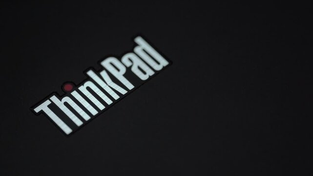 Close up of ThinkPad laptop logo with blinking red led indicator on cover under changing colorful RGB light.