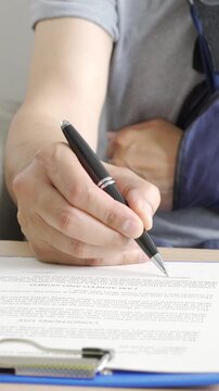 Disability man with sling signing contract at home