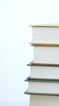 Books. A person's hand placing a book on a white background.