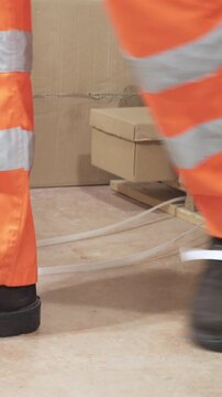 An industrial safety topic. A worker in danger of tripping over a piece of plastic strapping in a factory.