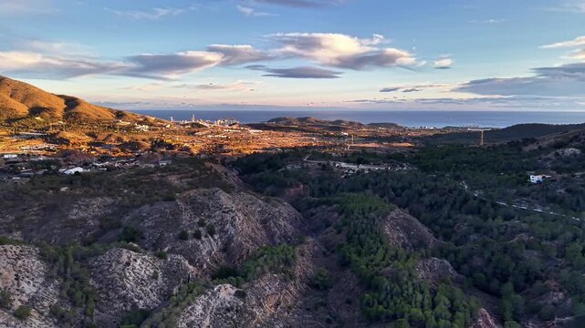 Dusk coastline valley with treecovered ridges and rocky foreground, conservation survey captures wetlands,