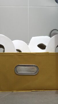 Woman, sitting on the toilet. Hands, taking and ripping off a piece of toilet paper from the roll, then one more large amount of paper. Indoors, indigestion concept.