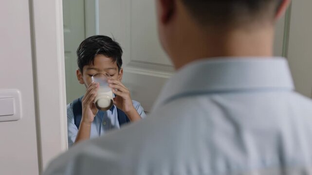 Reaching boy shirt backpack taking milk from glass at door before school, dad dress shirt watching